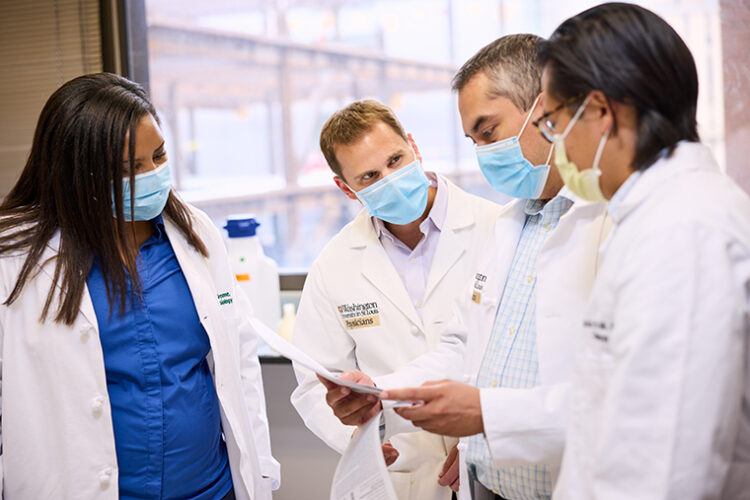 Kory Lavine, MD/PhD ’08, center, professor of medicine and director of the Cardiovascular Precision Medicine Research Initiative, consults with investigators in his lab. (Photo: Matt Miller/Washington University School of Medicine)