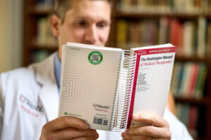 Thomas Ciesielski, MD, an associate professor of medicine at WashU Medicine, admires the recently published 38th edition of “The Washington Manual of Medical Therapeutics,” a bestselling medical book used by doctors around the world. Ciesielski served as the executive editor.