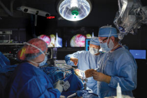 Neurosurgeon Albert Kim, MD, PhD (center), and chief resident Adam Bevan, MD, PhD, perform a right parietal craniotomy to remove a brain tumor.